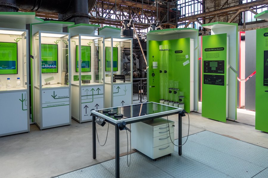 Blick in die Ausstellung: Man sieht verschiedene Stelen mit Exponaten und einen Medientisch.