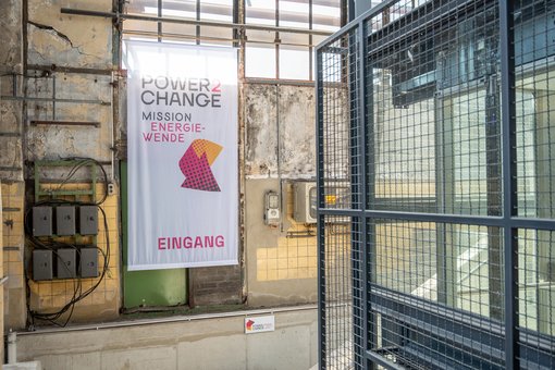 Blick in die Ausstellungsräume. An der Wand hängt ein großer Power2Change-Banner.